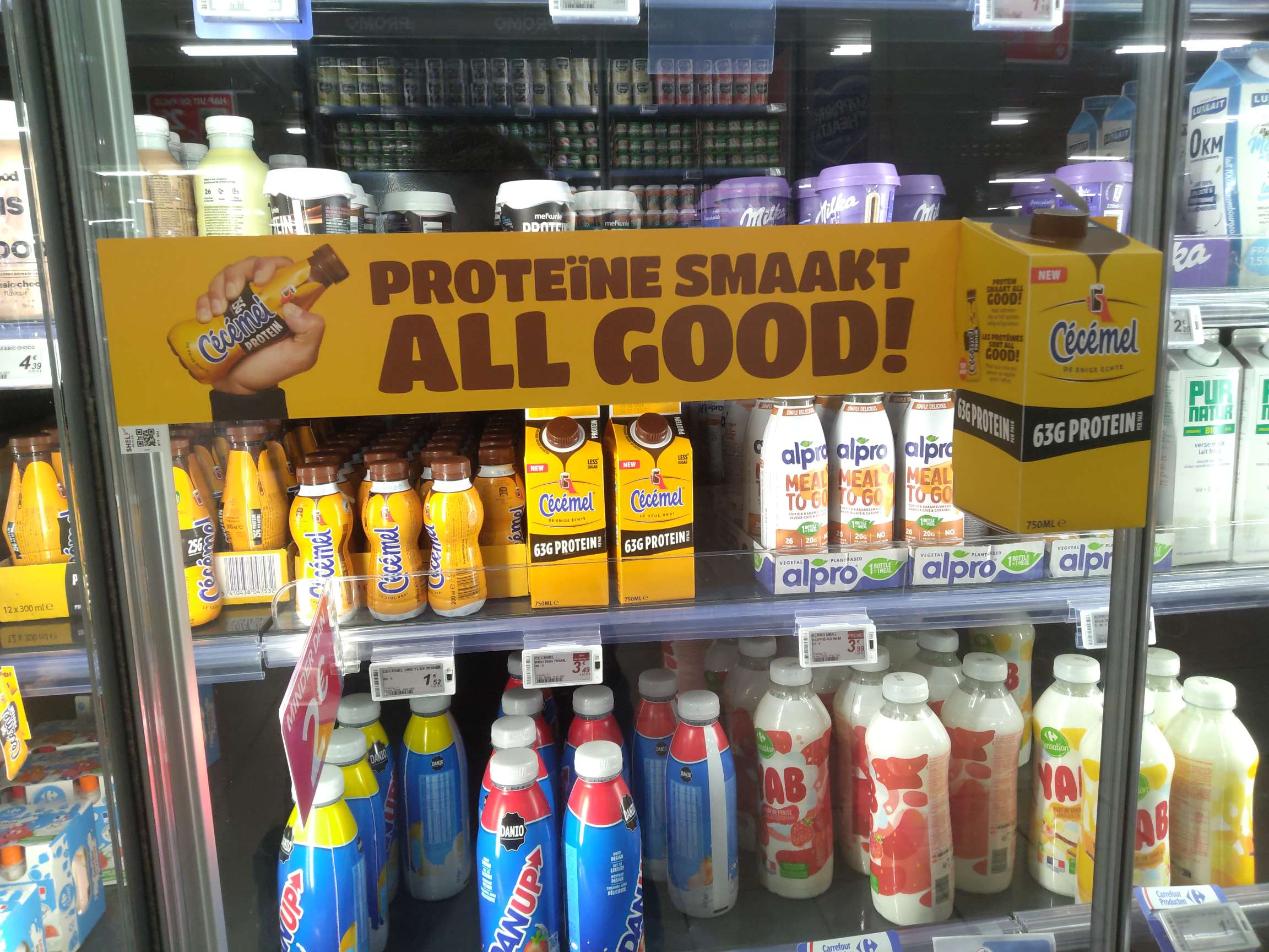 Gele banner «Proteïne smaakt all good!» voor Cécémel Protein op een koelschap in de supermarkt