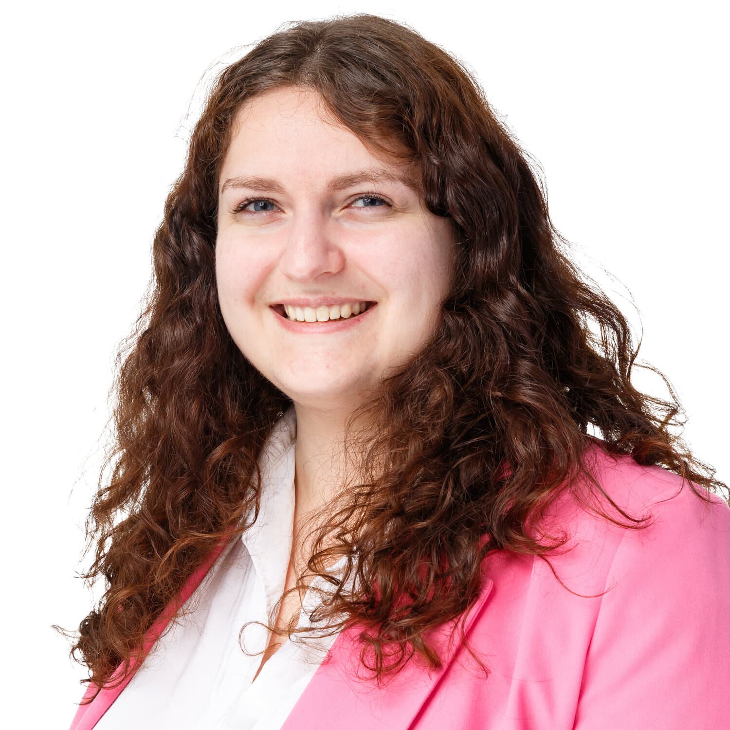 Portrait of a smiling woman with long curly brown hair, wearing a pink blazer and white blouse