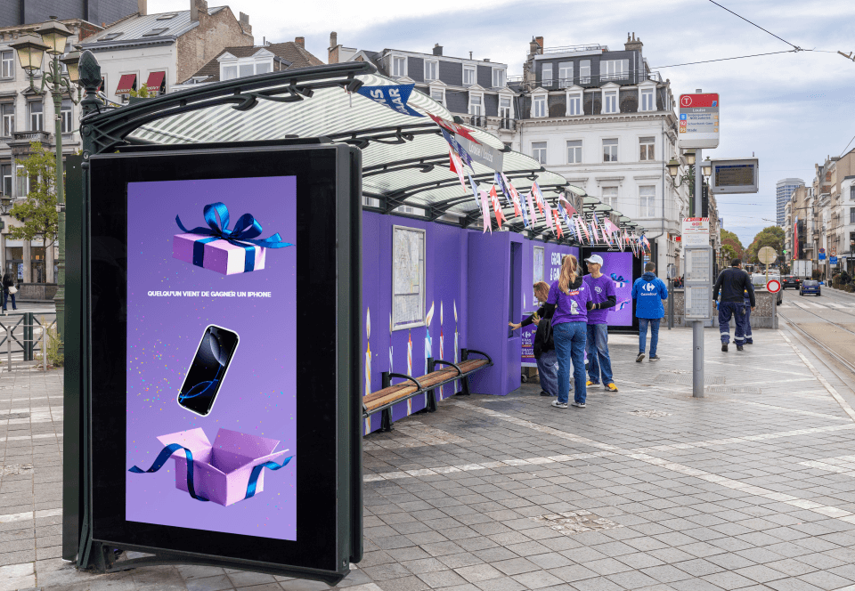 Abribus habillé en violet avec écran « Quelqu'un vient de gagner un iPhone » et hôtesses Carrefour