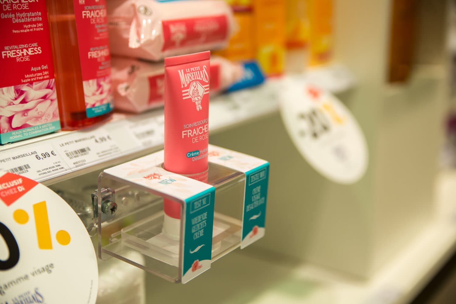 Le Petit Marseillais cream tester in a clear acrylic holder on a store shelf